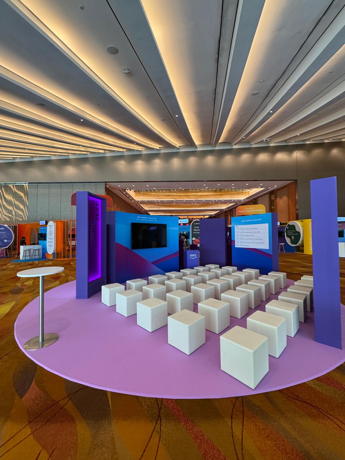 AWS-themed exhibition booth with modern seating cubes and interactive presentation setup at a tech event