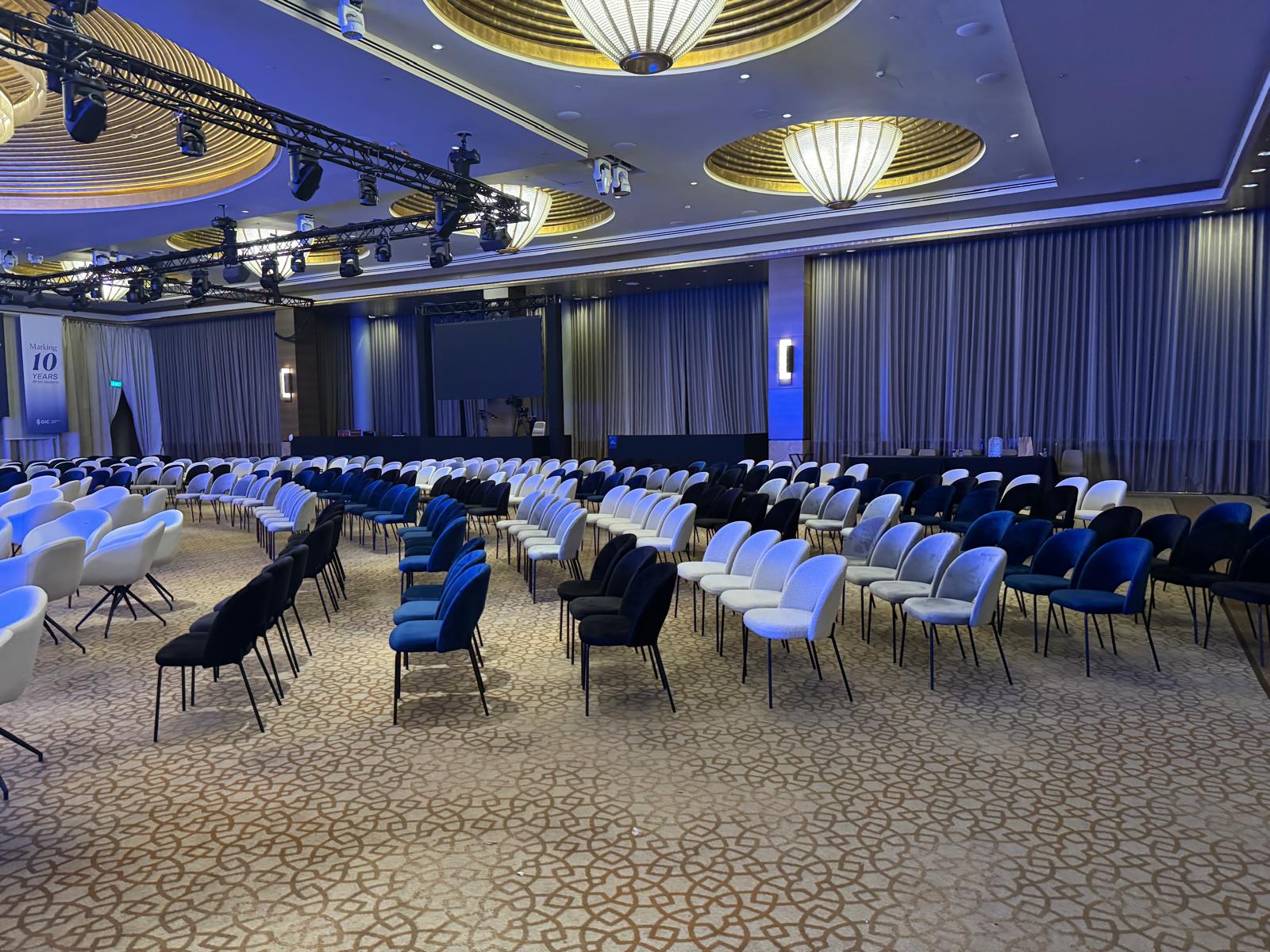 Modern corporate conference hall setup with organized seating, stage lighting, and event production rigging