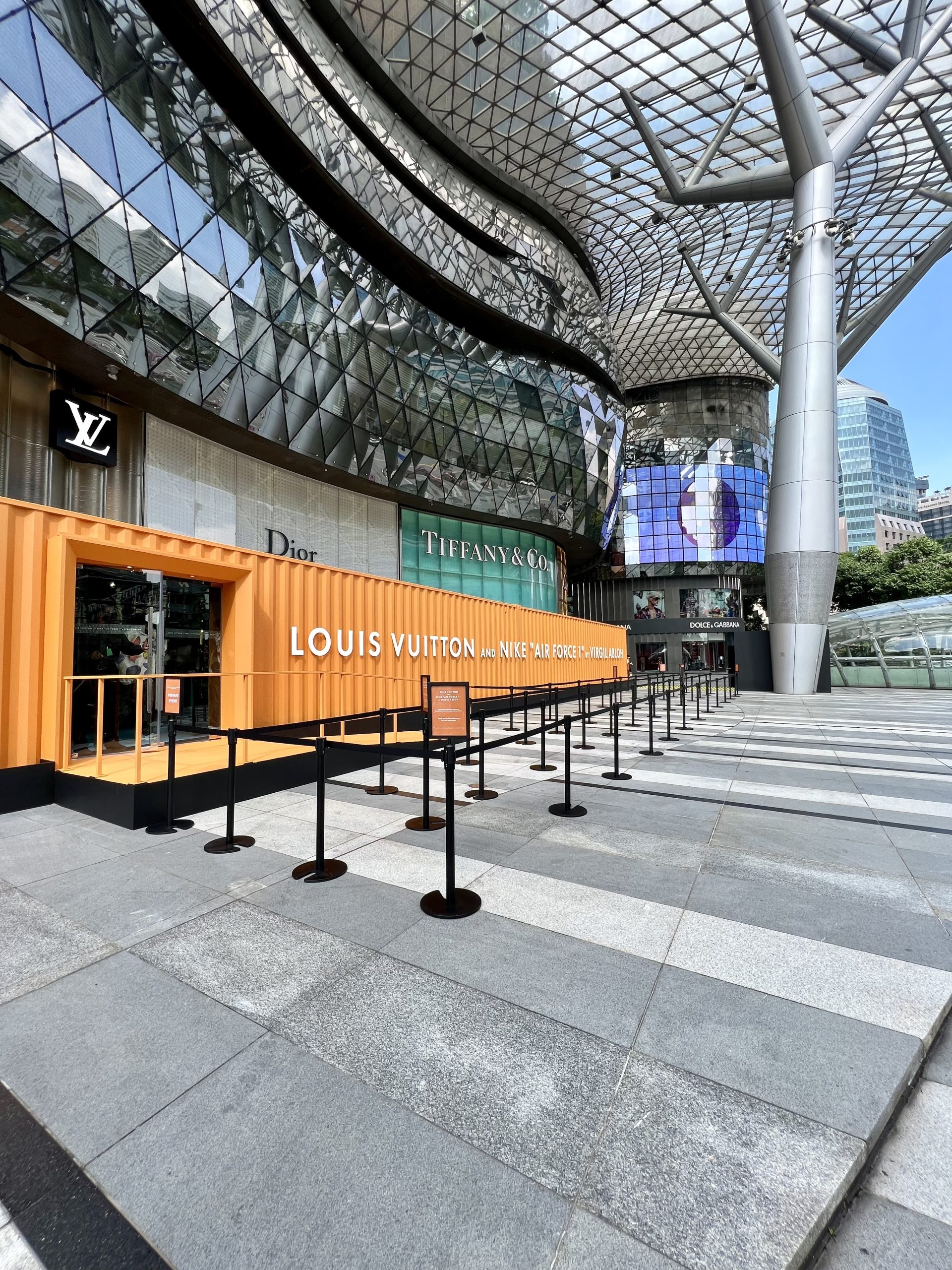 Luxury retail brand activation storefront with Louis Vuitton display and modern architectural shopping mall exterior