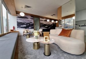 Modern luxury lounge with curved sofa, marble tables, pendant lighting, and mountain wall art in a stylish corporate setting