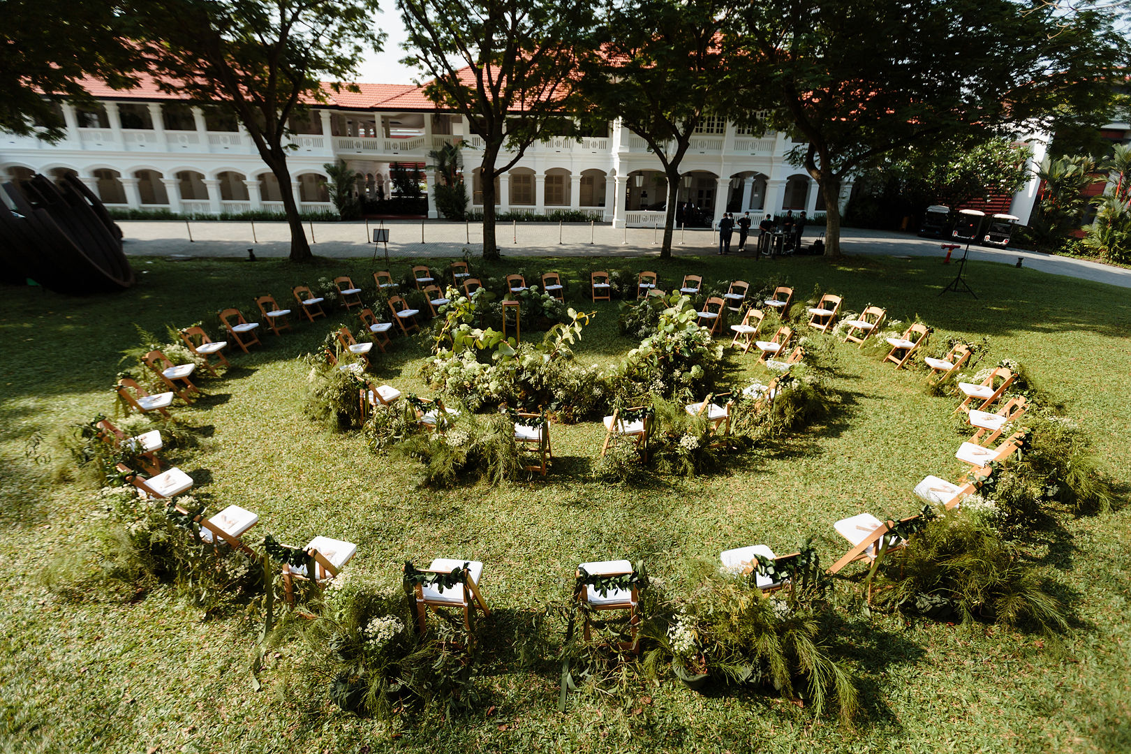 Outdoor wedding ceremony setup with circular seating, greenery décor, and garden venue