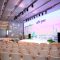 Modern corporate event stage with large LED screen, conference seating, and professional lighting setup
