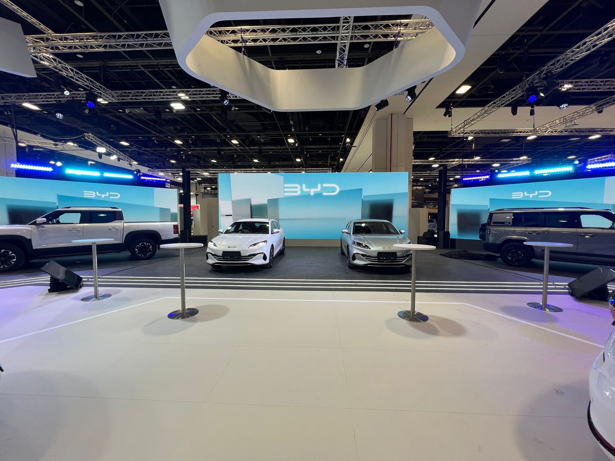 BYD electric vehicles showcased at a modern auto exhibition booth with LED backdrop and stage lighting