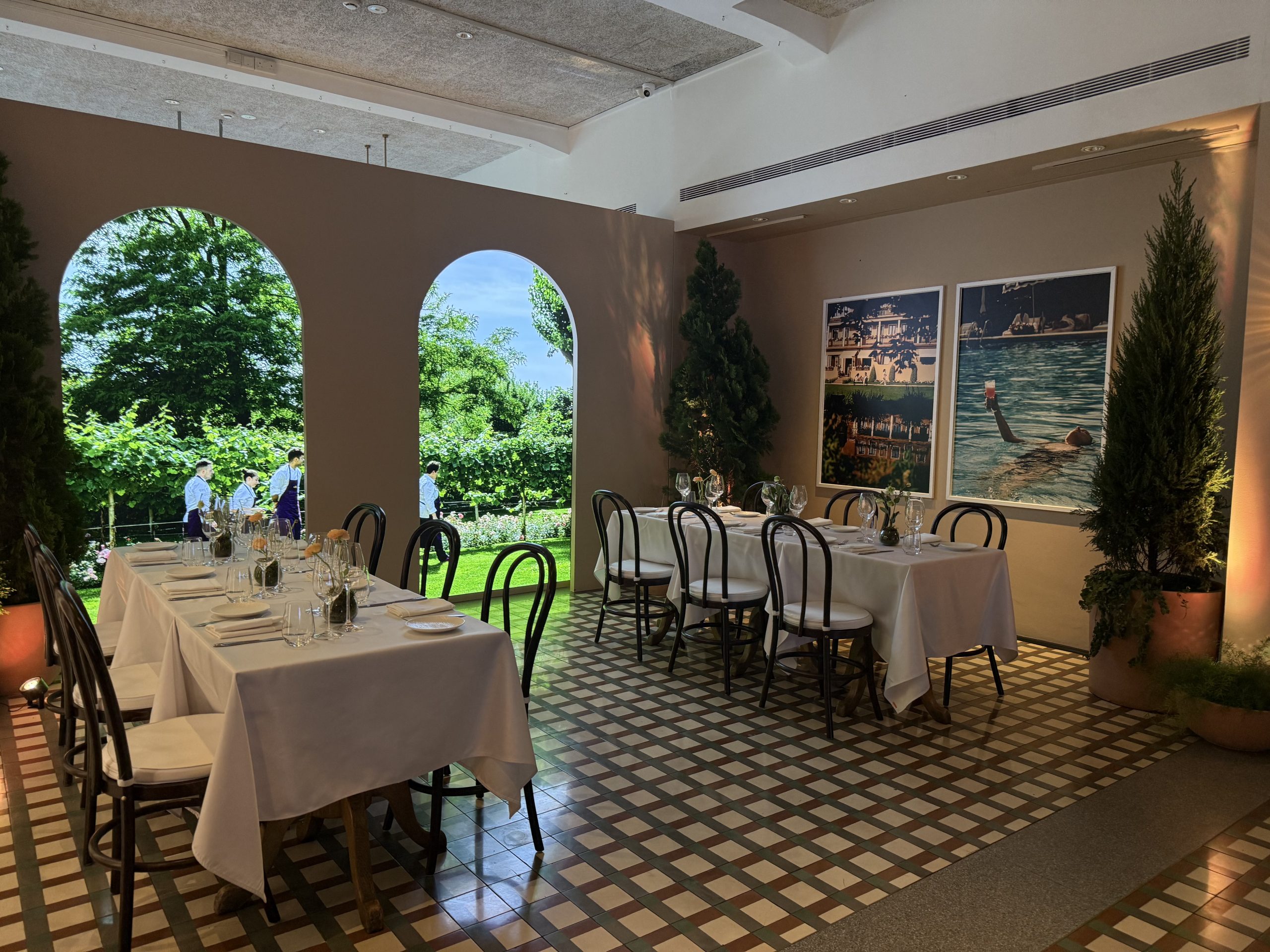 Elegant private dining setup with table arrangements, arched windows, and garden view in a luxury hospitality setting