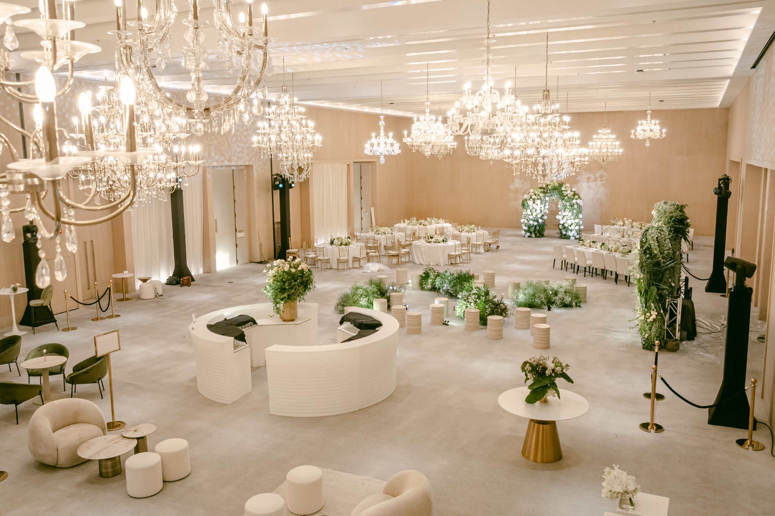 Luxury indoor wedding reception setup with chandeliers, floral décor, and elegant seating arrangement