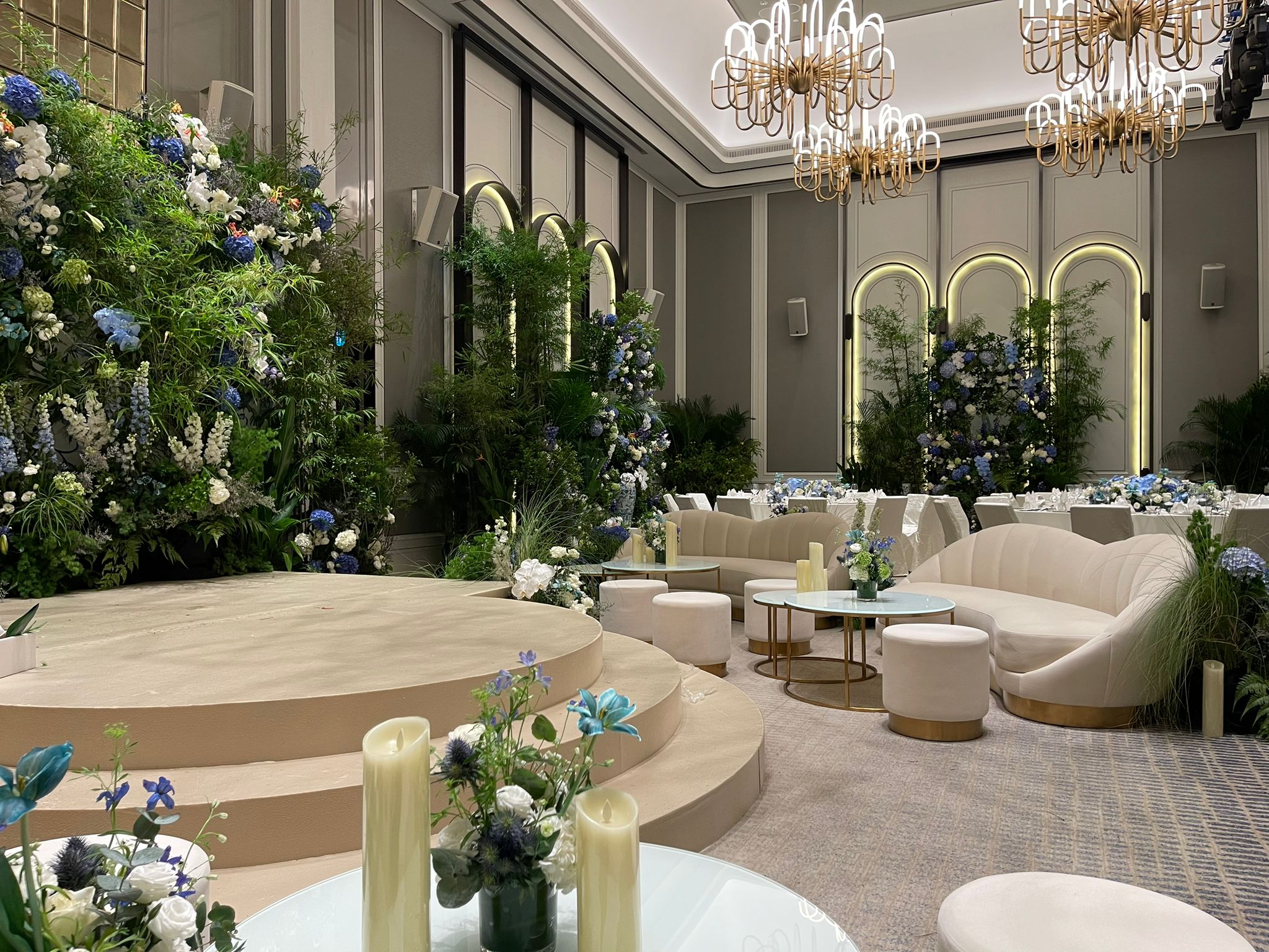 Luxury wedding stage with floral backdrop, elegant seating lounge, and indoor event décor