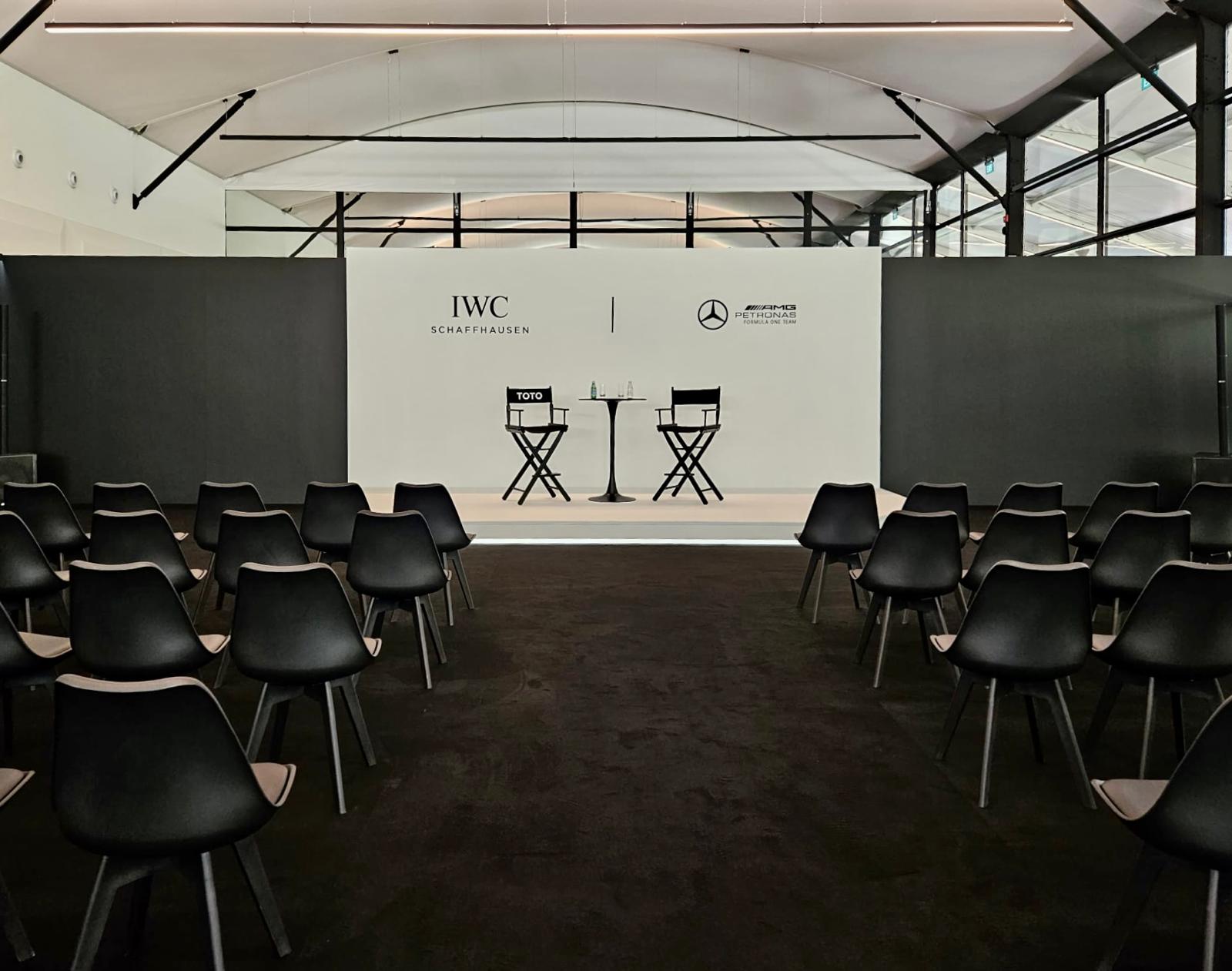 Minimalist corporate event stage setup with audience seating and branded backdrop for a panel discussion