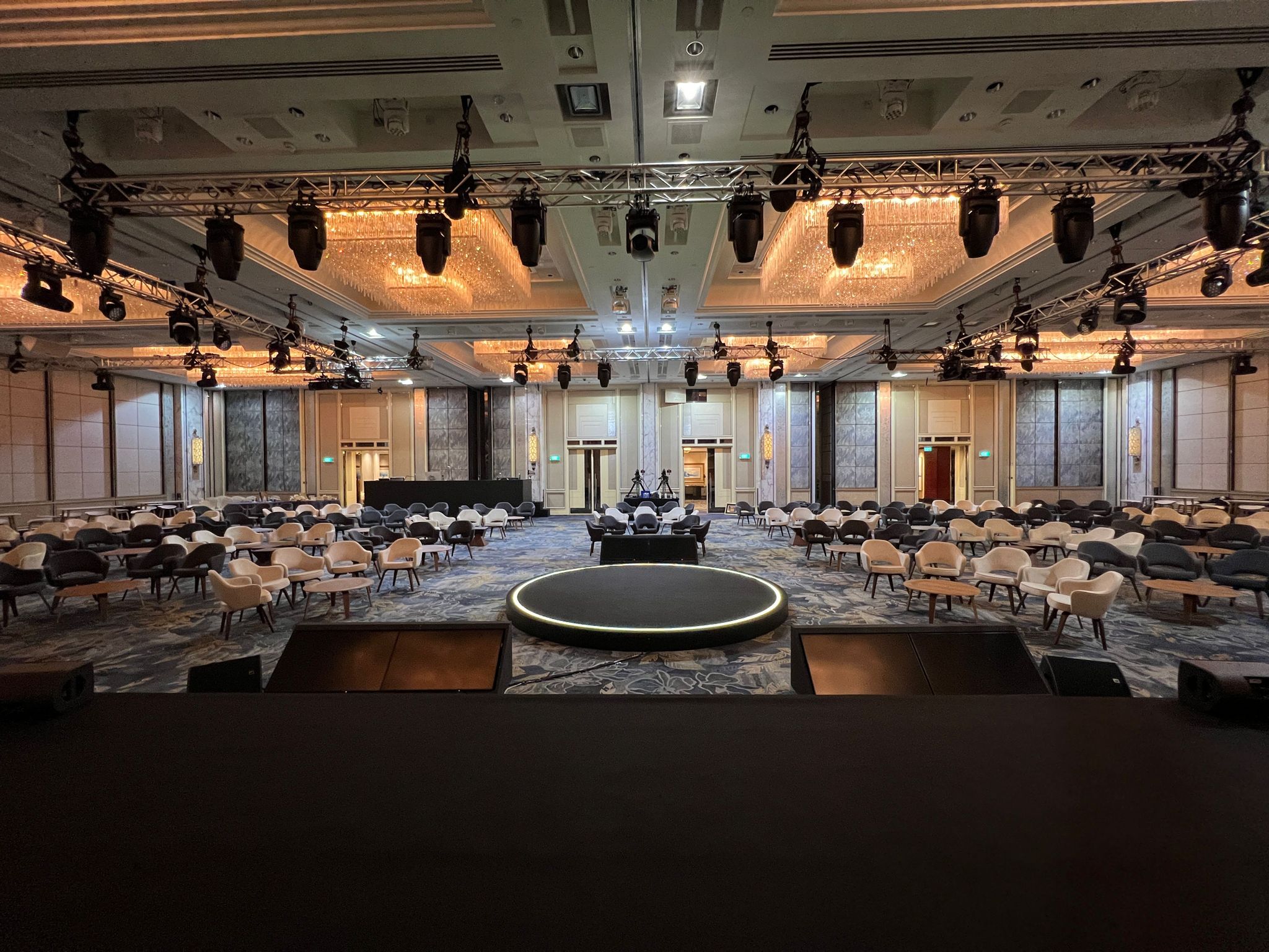 Large corporate conference setup with circular stage, audience seating, and professional lighting rig